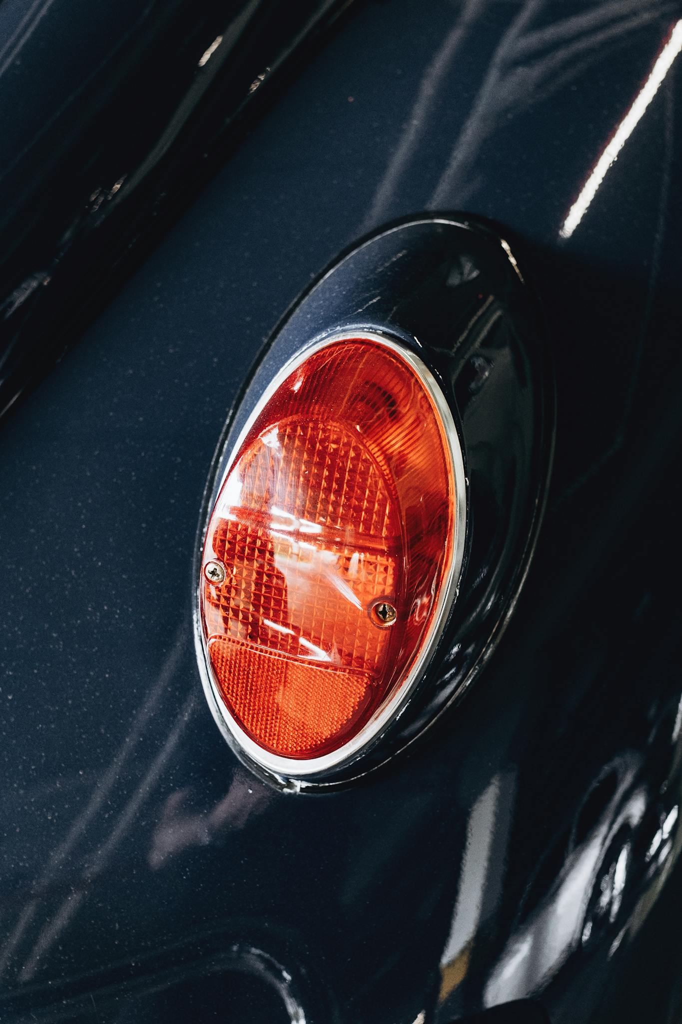 Detailed close-up of an oval red tail light on a black car, showcasing design and craftsmanship.